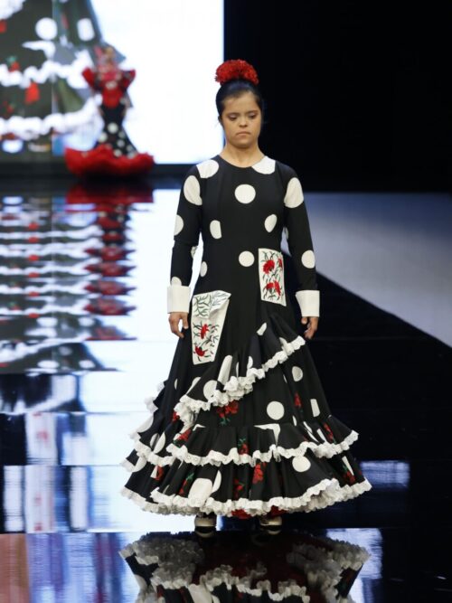 Traje de flamenca negro con lunares blancos y claveles rojos