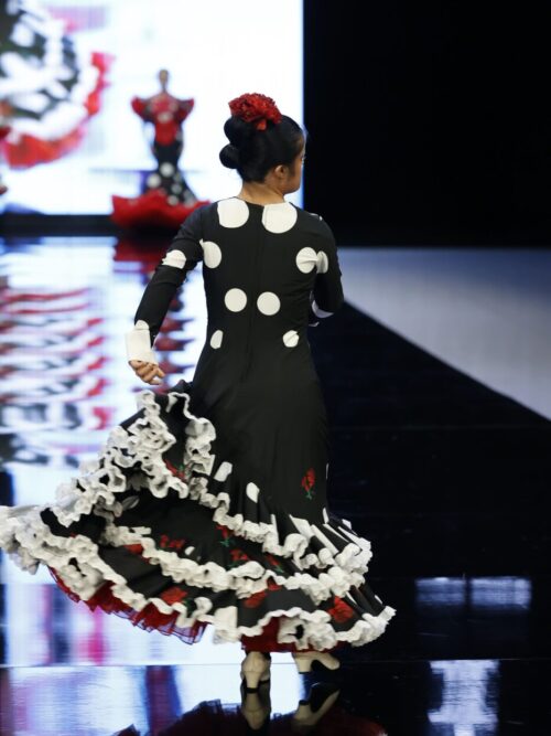 Traje de flamenca negro con lunares blancos y claveles rojos